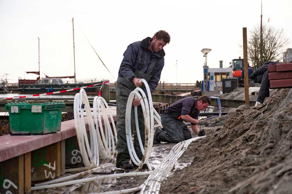 Twee mannen bezig met aanleg collectoren bij damwanden