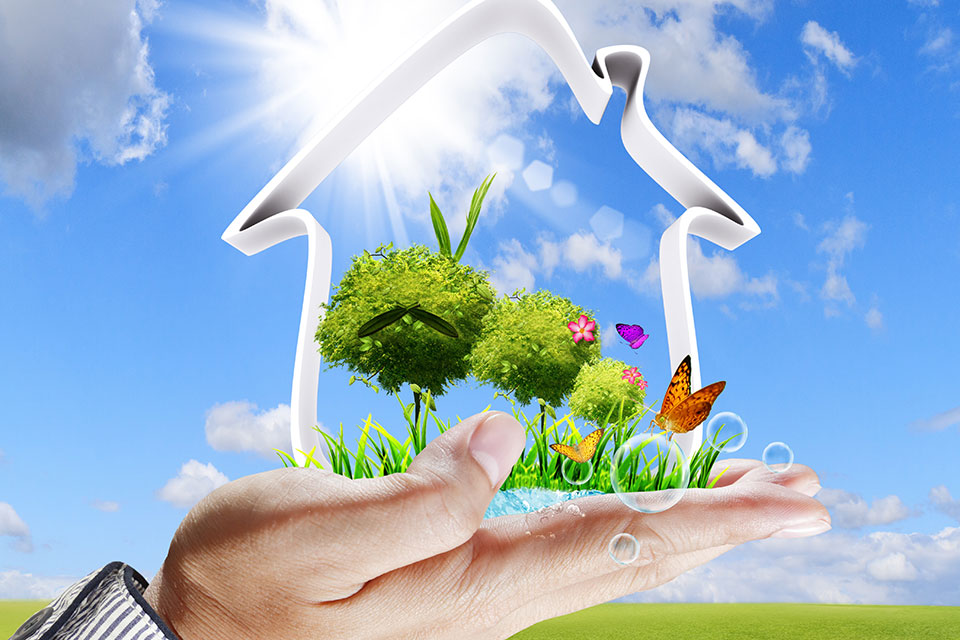 Contour van een huis met binnen groen, gedragen op een hand, achtergrond blauwe lucht