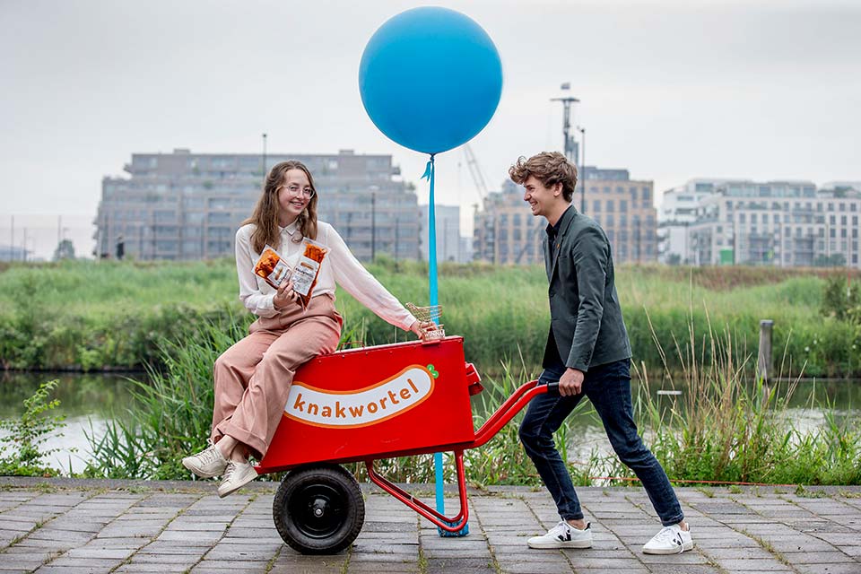 Valerie zittend op een rode kar met blauwe balon, Koen duwt de kar